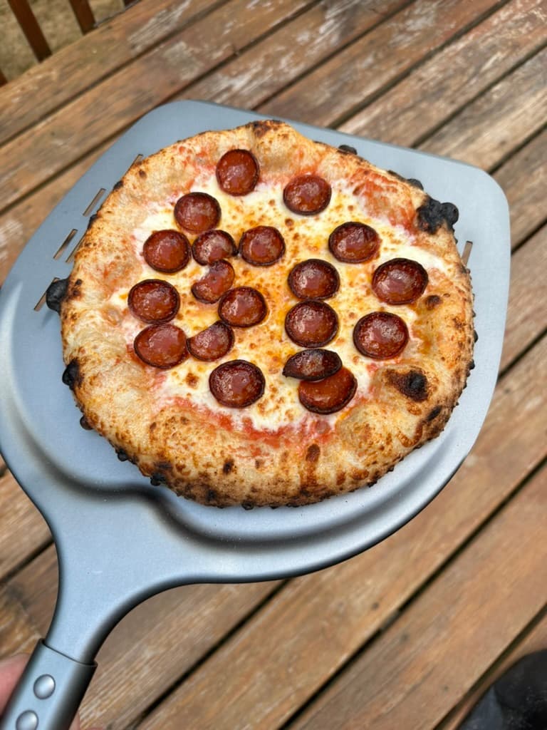 Finished pepperoni pizza on a pizza peel