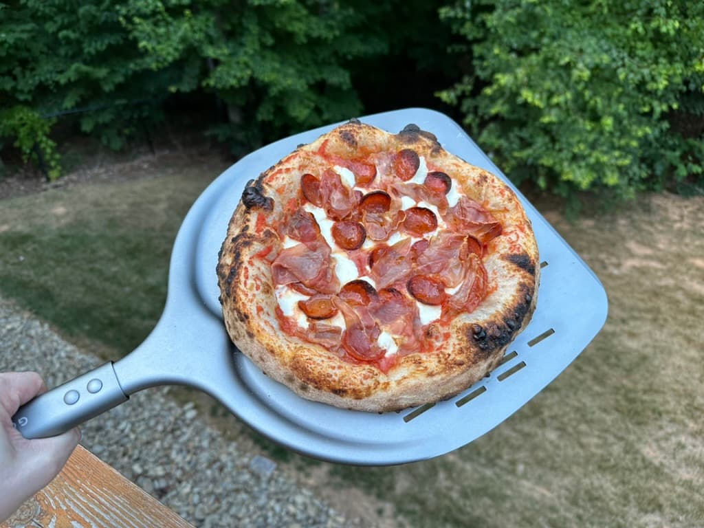 Finished pepperoni and prosciutto pizza on a pizza peel